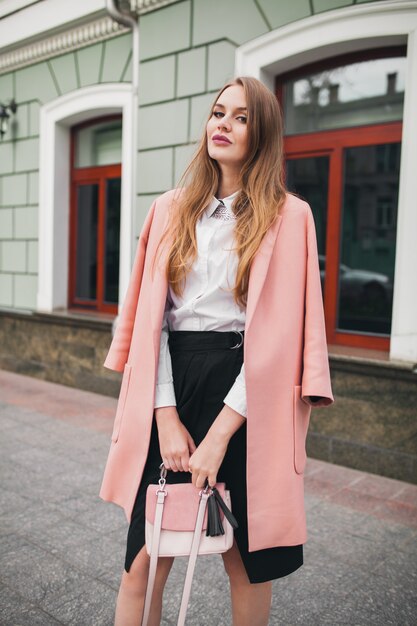 핑크 코트에 도시 거리를 걷는 매력적인 세련된 웃는 여자