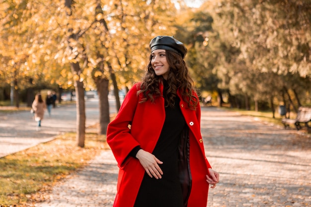 따뜻한 빨간 코트 가을 유행 패션, 거리 스타일을 입고 공원에서 산책하는 곱슬 머리를 가진 매력적인 세련된 웃는 여자, 베레모 모자를 쓰고