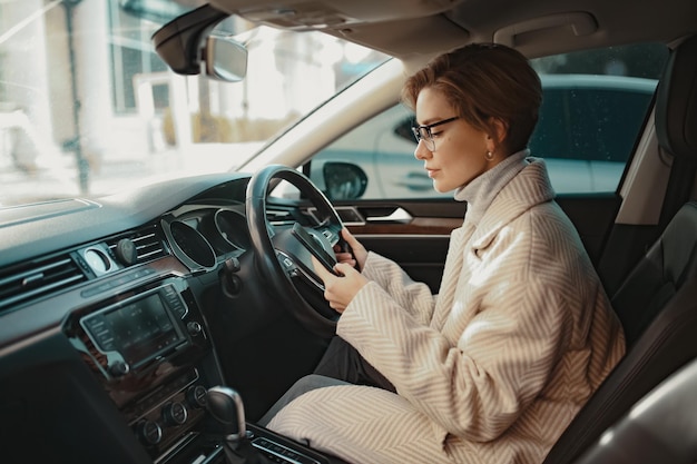 Attractive stylish woman sitting in car dressed in coat