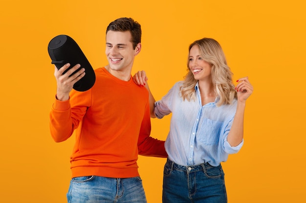 Attractive stylish young couple holding wireless speaker