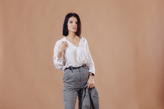 Attractive stylish young girl in business attire posing on cream background. concept of stylish clothes and sophistication.