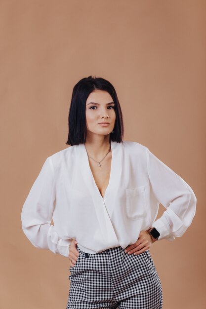 Attractive stylish young girl in business attire posing on cream wall. concept of stylish clothes and sophistication.