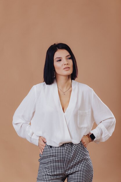 Attractive stylish young girl in business attire posing on cream wall. concept of stylish clothes and sophistication.