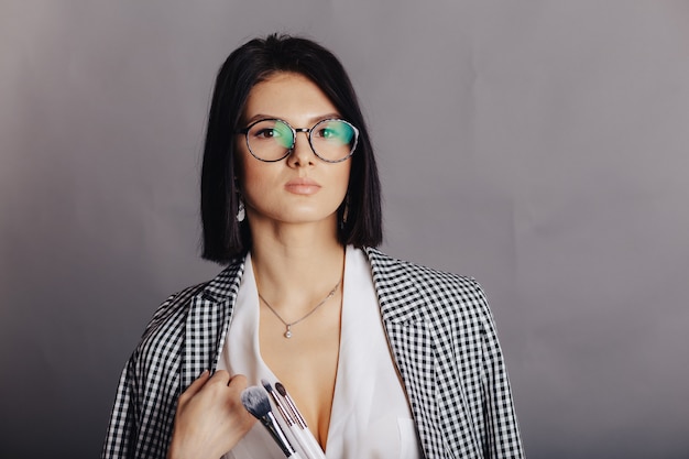 Attractive stylish young girl in business clothes posing on dark wall. concept of stylish clothes and sophistication.