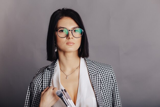 Attractive stylish young girl in business clothes posing on dark wall. concept of stylish clothes and sophistication.