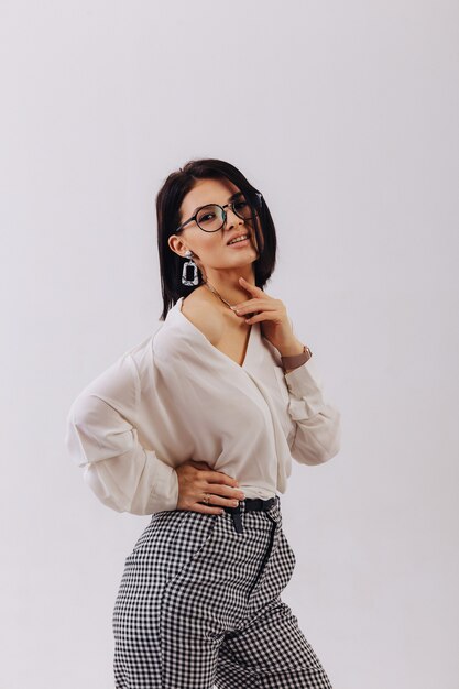 Attractive stylish young girl in business clothes posing on light background in studio. concept of stylish clothes and sophistication.