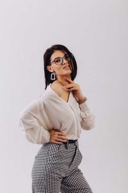 Attractive stylish young girl in business clothes posing on light background in studio. concept of stylish clothes and sophistication.