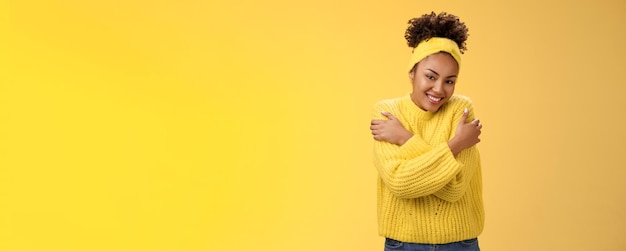 Free photo attractive tender gentle africanamerican teenage girl in sweater headband hugging herself hands touc