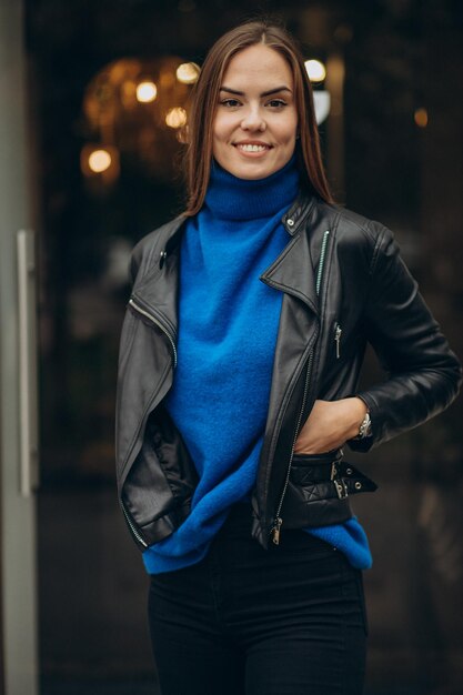 Привлекательная женщина стоит на улице в черной куртке