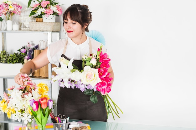 Foto gratuita donna attraente che organizza i fiori nel negozio floreale