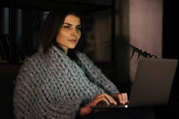 Free photo attractive woman in blanket browsing laptop