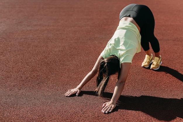 Attractive woman downward facing dog pose at sport ground