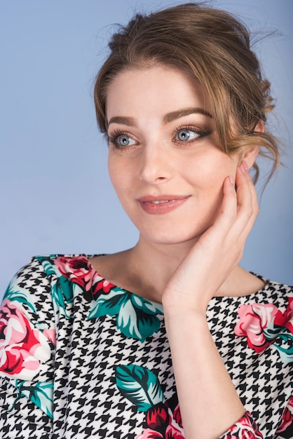 Attractive woman in dress holding cheek 