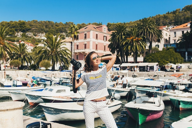 Attractive woman in dress treveling on vacation in Europe by the sea on a cruise taking pictures on camera