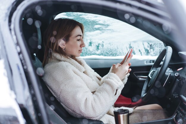 彼女の車のステアリングホイールの後ろに座っている魅力的な女性ドライバー