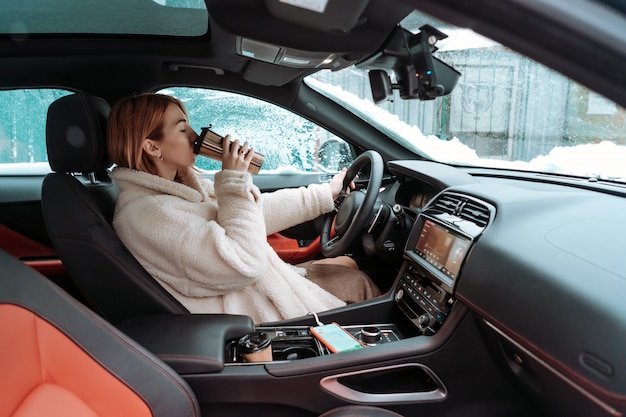 Foto gratuita autista donna attraente seduto dietro il volante della sua auto