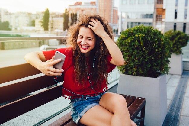 Attractive woman in headphones having online video chat with friends using a smartphone