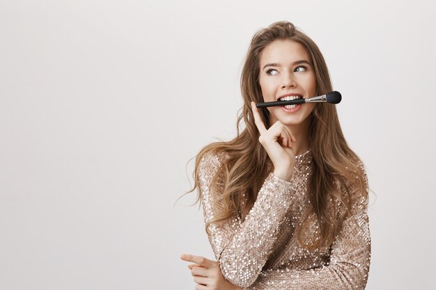 Attractive woman hold brush in mouth, look away