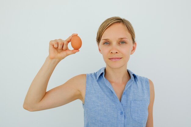 Привлекательная женщина, проведение яйцо с двумя пальцами