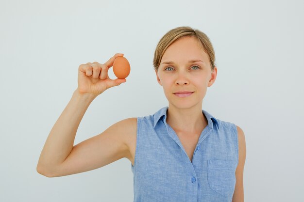 2つの指で卵をつけている魅力的な女性