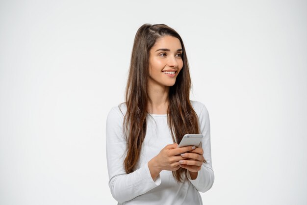 Привлекательная женщина держит мобильный телефон, улыбаясь