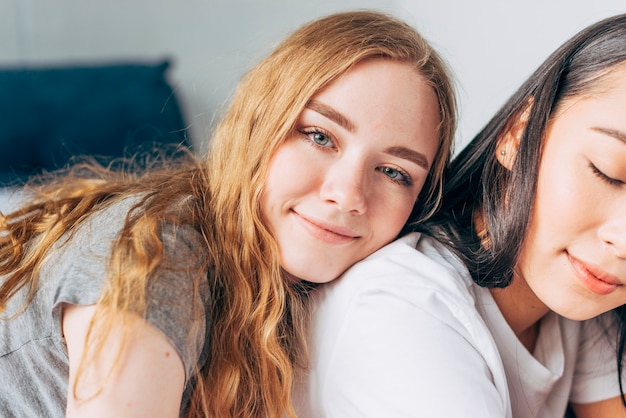 Attractive woman hugging girlfriend and looking at camera