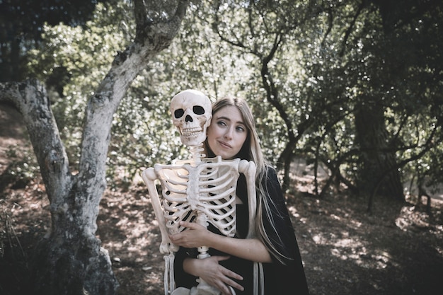 Attractive woman hugging behind skeleton 