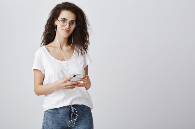 Attractive woman listening music in earphones and messaging via mobile phone