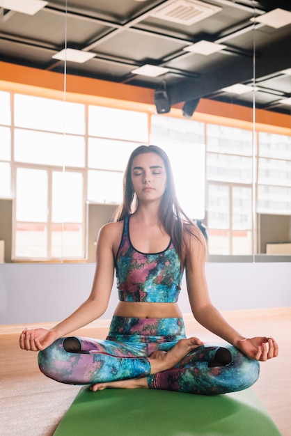 Привлекательная женщина медитирует в позе лотоса с закрытыми глазами
