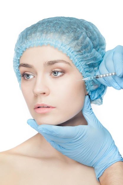 Attractive woman at plastic surgery with syringe in her face on white background