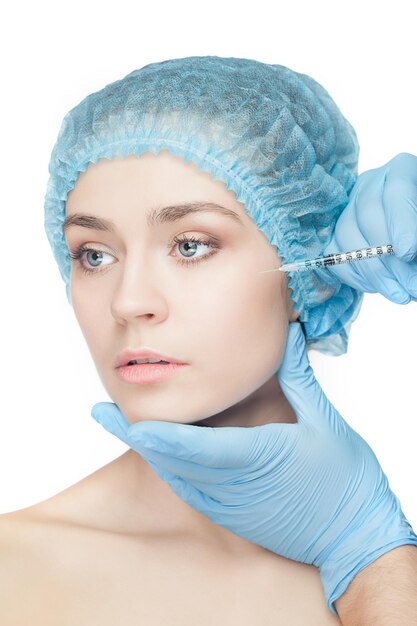 Привлекательная женщина в пластической хирургии со шприцем в ее лице на белом фоне