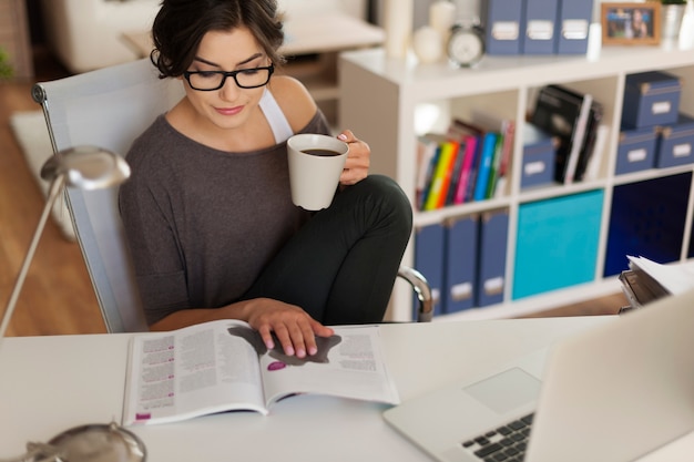 Attractive woman reading magazine at home