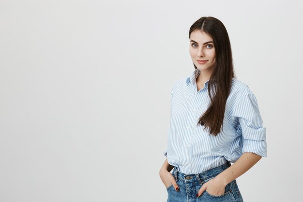 Attractive woman in shirt and jeans holding hands in pockets