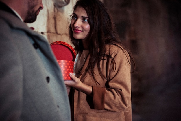 Attractive woman showing present box to man