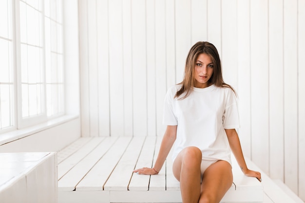 Attractive woman sitting in white room