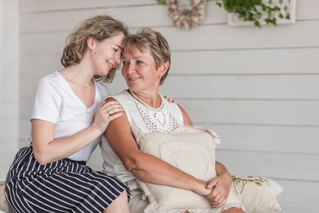 Attractive woman sitting with her mother on sofa looking at each other