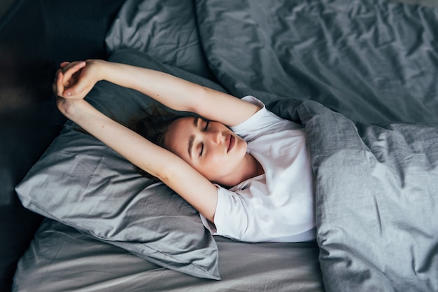 Attractive woman stretching in the morning and is smiling in her bed