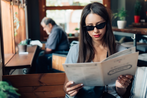 Free photo attractive woman in sunglasses is sitting in a restaurant.