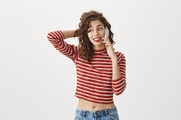 Attractive woman talking on phone, hesitating, scratch head unsure or awkward