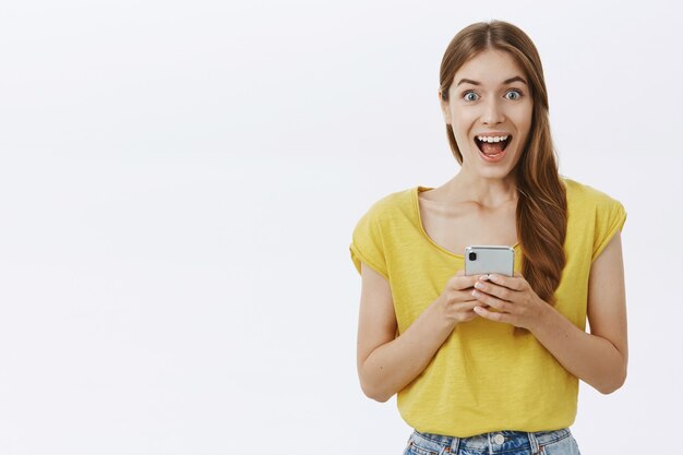 Привлекательная женщина, использующая мобильный телефон, текстовое сообщение в приложении или социальной сети, выглядит счастливой