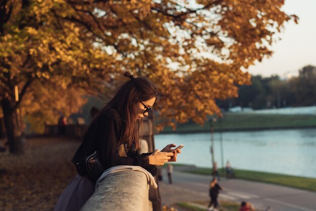 公園で屋外のスマートフォンを使用して魅力的な女性