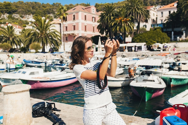 カメラで写真を撮るクルーズで海沿いのヨーロッパで休暇中の魅力的な女性