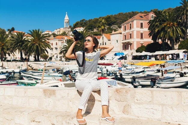 Attractive woman on vacation in Europe by the sea on a cruise taking pictures on camera