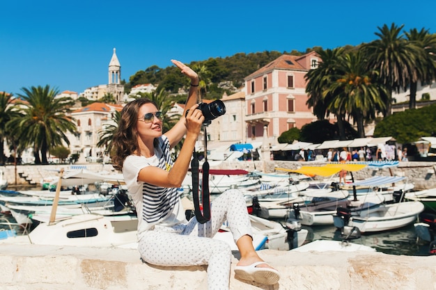 カメラで写真を撮るクルーズで海沿いのヨーロッパで休暇中の魅力的な女性
