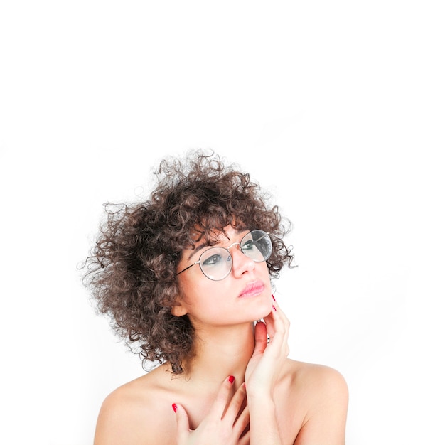 Foto gratuita una donna attraente che indossa gli occhiali che tocca la sua guancia isolato su sfondo bianco