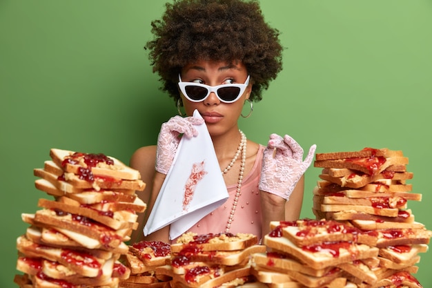 Attractive woman with Afro hair surrounded by peanut butter jellly sandwiches