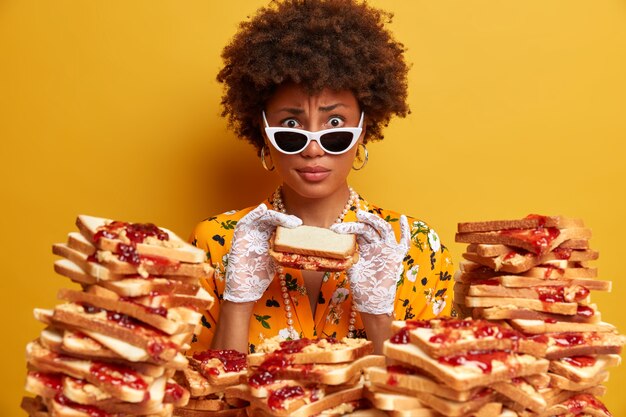 Attractive woman with Afro hair surrounded by peanut butter jellly sandwiches