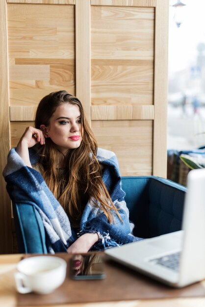 Attractive woman with blanket looking at her laptop