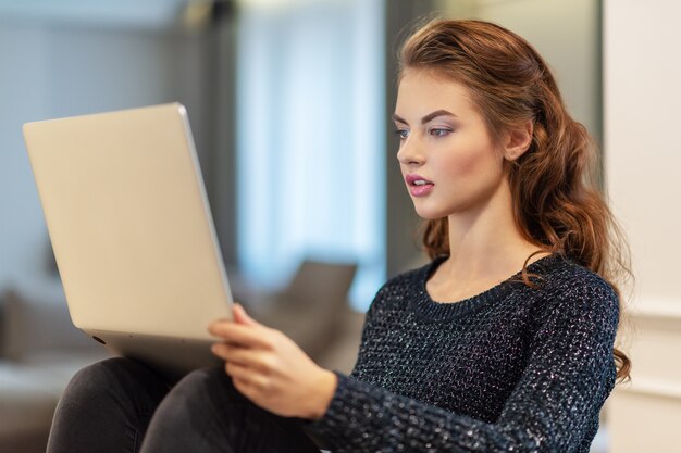 Attractive  woman with laptop at home. Young woman working on computer while sitting at home. Enjoying time at home.