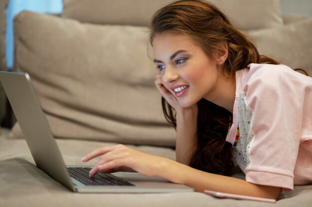 Attractive  woman with laptop at home. Young woman working on computer while sitting at home. Enjoying time at home.